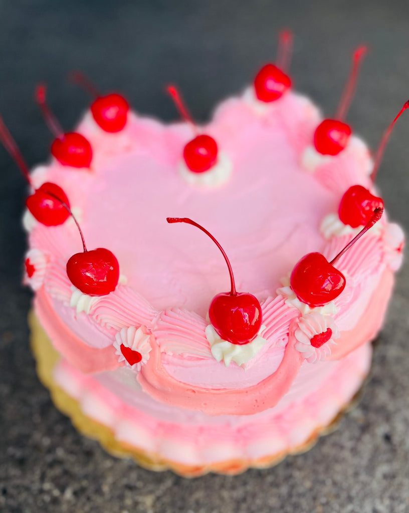 photo of a heart shaped pink cake with cherries